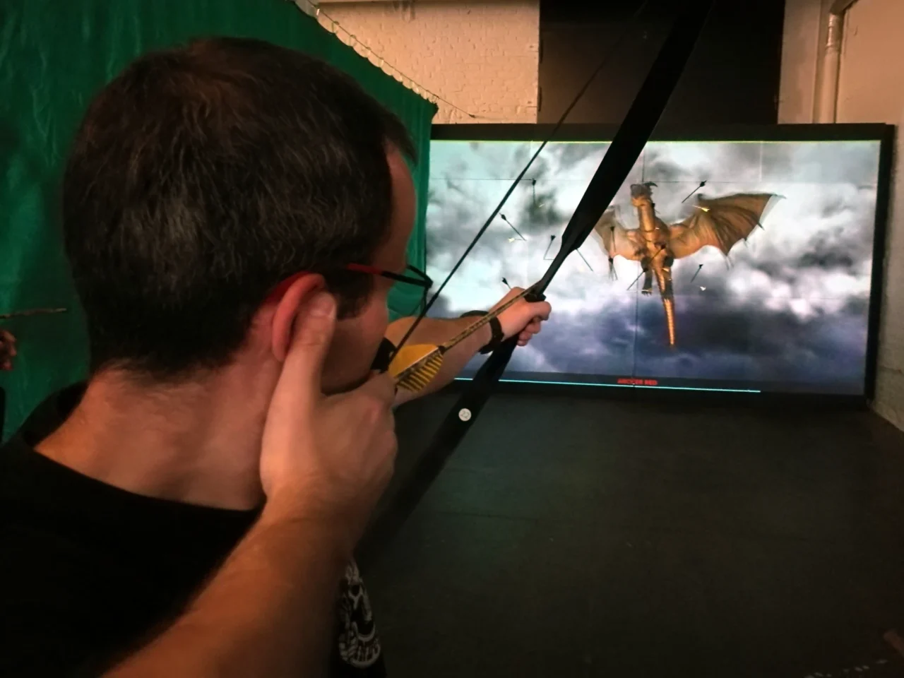 Person beim Bogenschießen auf einen fliegenden Drachen im digitalen Bogenkino der Bogenarena Wuppertal