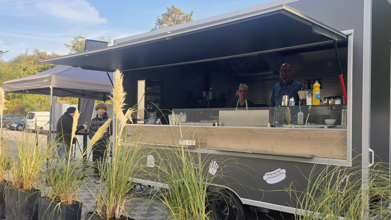 Hatzfelder Streetfood – Foodtrailer an der Bogenarena Außenansicht des Hatzfelder Streetfood Foodtrailers mit Personal und Gästen vor Ort auf dem Gelände der Bogenarena Wuppertal